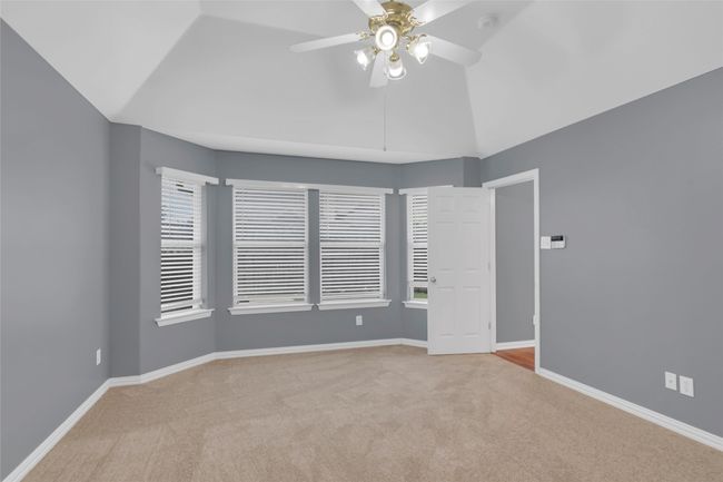Empty room with carpet floors, ceiling fan, lofted ceiling, and a smoke detector | Image 21