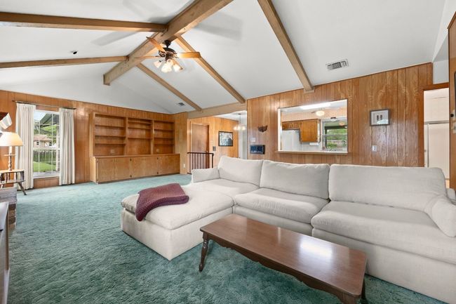 Living room with wood walls, carpet, a ceiling fan, and built in shelves | Image 9
