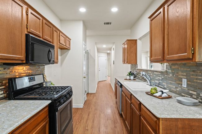 Galley-style layout with a modern backsplash and built-in microwave. 9349 Bernoulli Dr., Austin, TX 78748 | Image 9