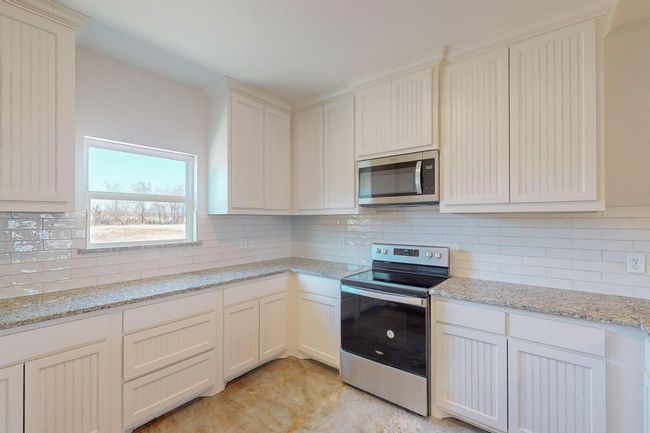 Kitchen with appliances with stainless steel finishes, backsplash, and light stone countertops | Image 15