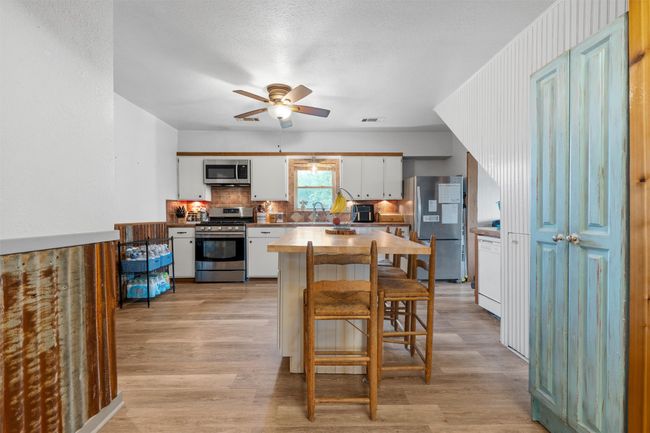 Kitchen featuring a sink, appliances with stainless steel finishes, light wood-style floors, and ceiling fan | Image 7