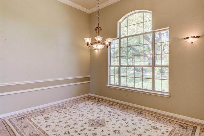 Arched windows, ample light and space make the dining room elegant yet accessible. Enter from the foyer or the kitchen. Views of the towering oaks in the front yard. | Image 11