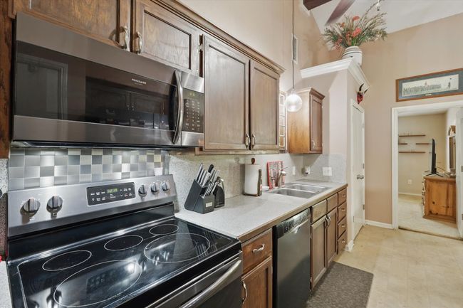 Kitchen featuring a sink, decorative backsplash, light countertops, baseboards, and appliances with stainless steel finishes | Image 15