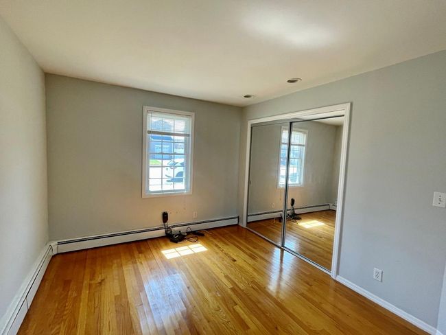 Unfurnished bedroom featuring wood-type flooring, a baseboard radiator, a closet, and baseboards | Image 18
