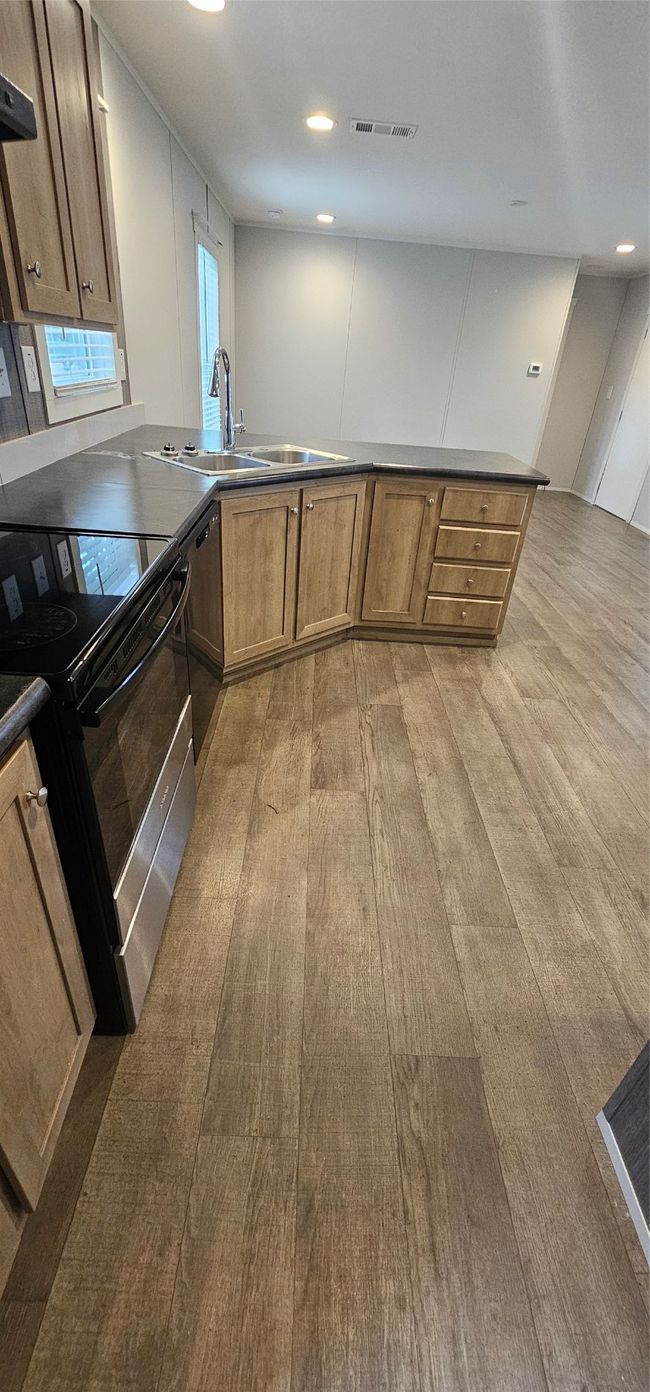 Kitchen featuring range, light wood-style flooring, dishwasher, dark countertops, and extractor fan | Image 13