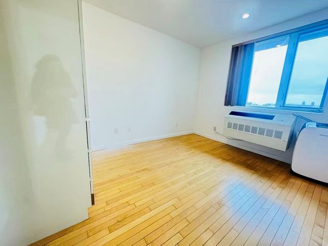 Empty room featuring baseboards, wood finished floors, and a wall mounted AC | Image 6