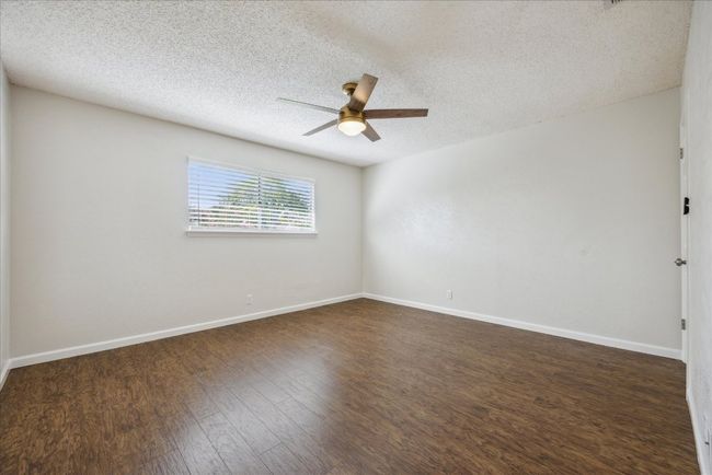 Spare room featuring ceiling fan, dark wood-style floors, and a textured ceiling | Image 24