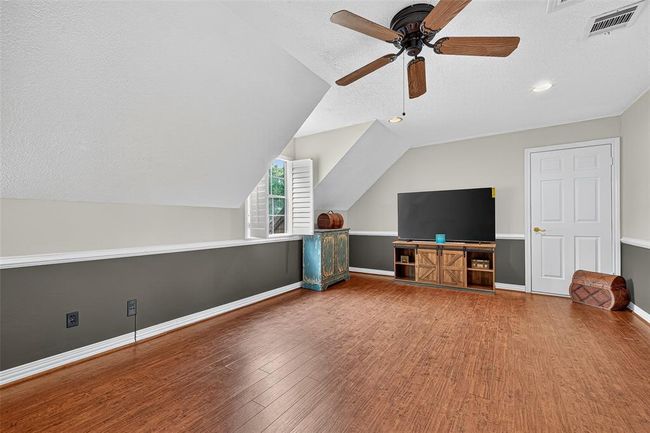 Upstairs, this spacious game room is filled with possibility. With wood floors underfoot, a ceiling fan overhead, and a large window for brightness, it’s ready for play, creativity, or retreat. | Image 27