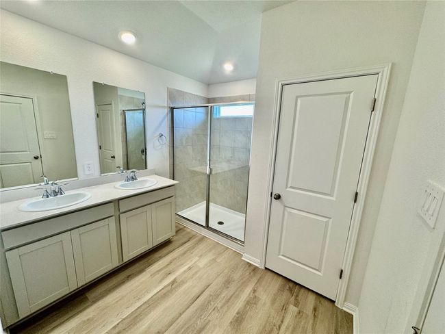 Full bath featuring a stall shower, wood finished floors, double vanity, and recessed lighting | Image 4