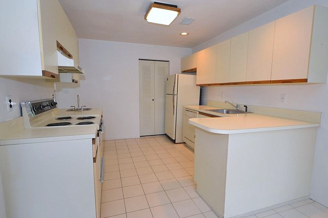 Kitchen featuring a sink, visible vents, white appliances, under cabinet range hood, and light countertops | Image 7