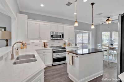 Kitchen with ceiling fan, dark wood-type flooring, sink, stainless steel appliances, and white cabinetry | Image 2