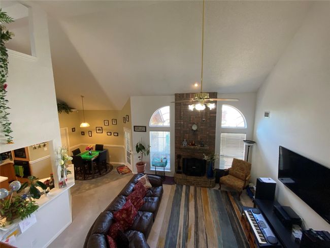 Living room with a brick fireplace, carpet floors, high vaulted ceiling, and ceiling fan | Image 11