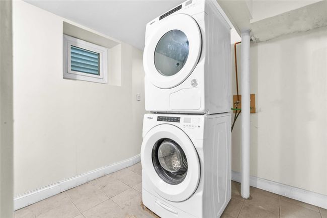 Laundry room featuring light tile patterned floors, stacked washer and clothes dryer, laundry area, and baseboards | Image 13