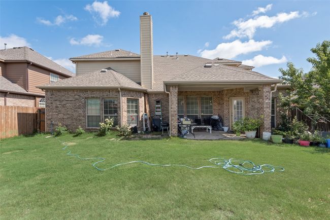 Rear view of property with a patio area, brick siding, a chimney, and roof with shingles | Image 30