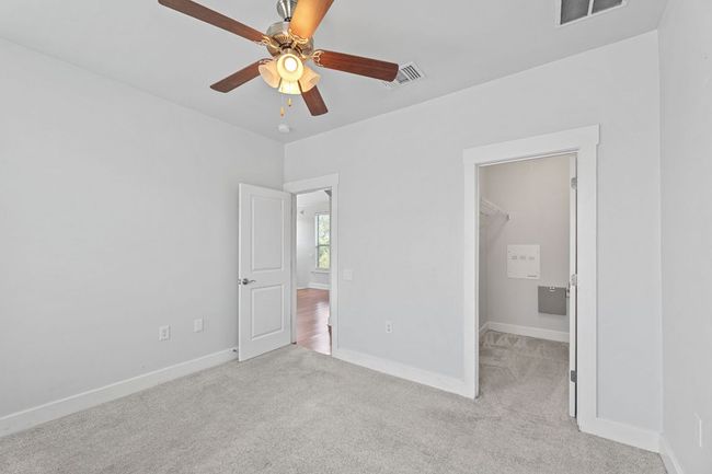 Unfurnished bedroom with a spacious closet, carpet flooring, and a ceiling fan | Image 5
