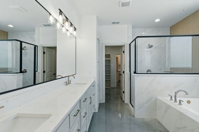 Full bathroom with a marble finish shower, a garden tub, double vanity, finished concrete floors, and a spacious closet | Image 12