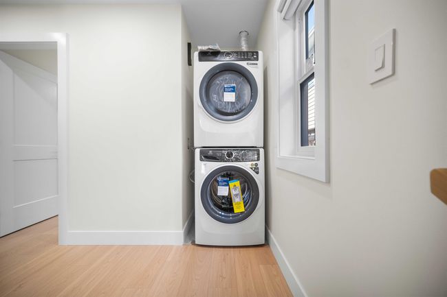 Laundry area featuring stacked washer and clothes dryer and wood finished floors | Image 27