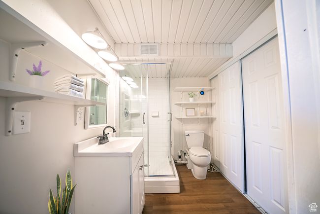 Bathroom with visible vents, toilet, a shower stall, vanity, and wood finished floors | Image 10