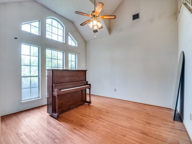 Living area with light wood-style flooring, high vaulted ceiling, and a ceiling fan | Image 4