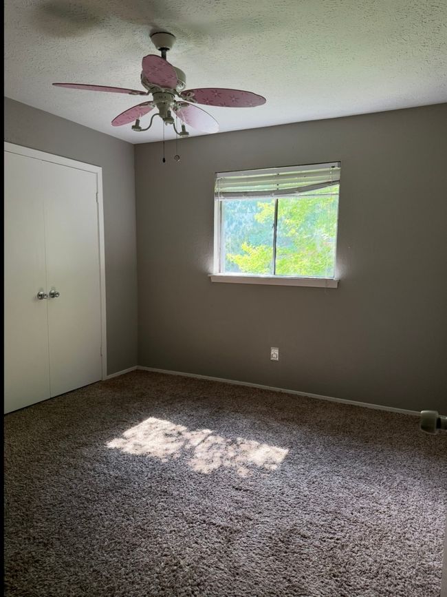 Carpeted spare room featuring ceiling fan and a textured ceiling | Image 15