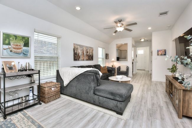 Living room with visible vents, baseboards, a ceiling fan, light wood-style floors, and vaulted ceiling | Image 10