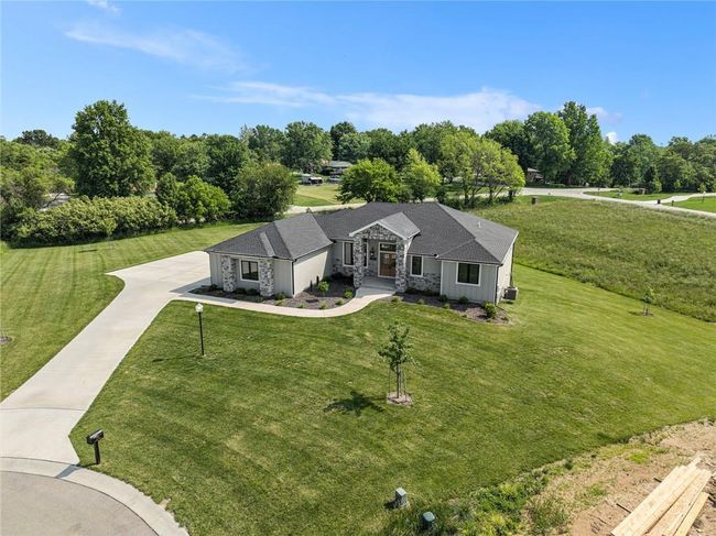 View of front facade featuring driveway, stone siding, a front lawn, and view of wooded area | Image 69