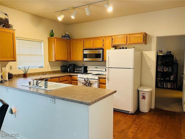 Kitchen with white appliances, a peninsula, dark wood-style floors, and track lighting | Image 4