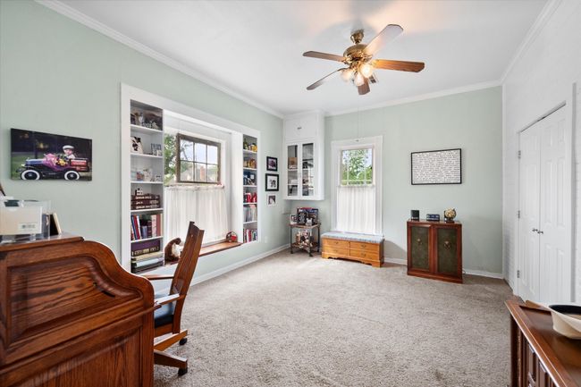 Recreation room with a ceiling fan, carpet flooring, and baseboards. Playroom. | Image 24