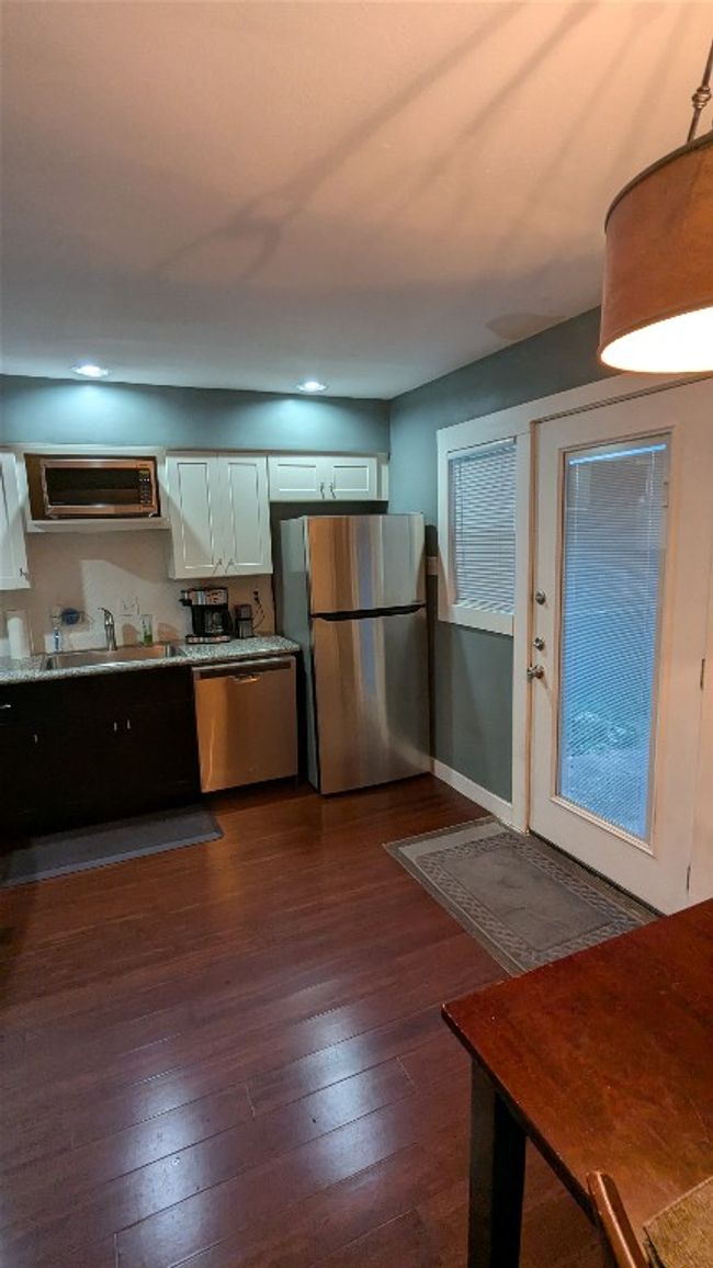 Kitchen featuring appliances with stainless steel finishes, a sink, dark wood-style flooring, a wall mounted air conditioner, and recessed lighting | Image 14