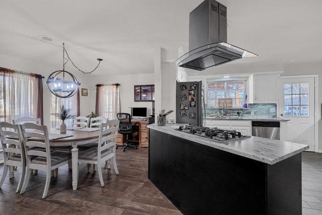 Kitchen with island range hood, dark wood-type flooring, dark cabinetry, and tasteful backsplash | Image 8