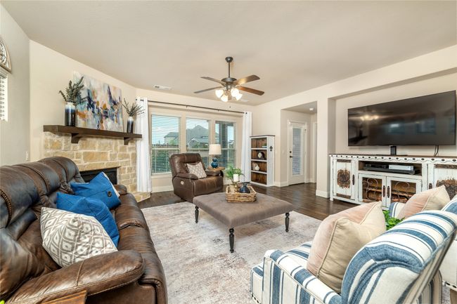 Living room featuring a fireplace, a ceiling fan, baseboards, and wood finished floors | Image 14