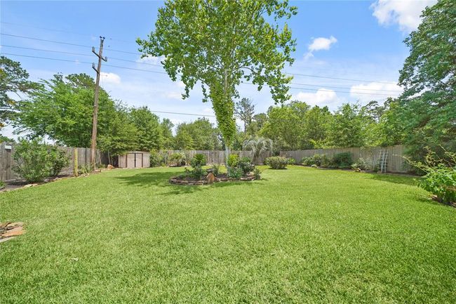 Spacious backyard with lush green lawn, mature trees, and well-maintained landscaping, offering privacy with a wooden fence and no back neighbors. Ideal for outdoor activities and relaxation. | Image 32