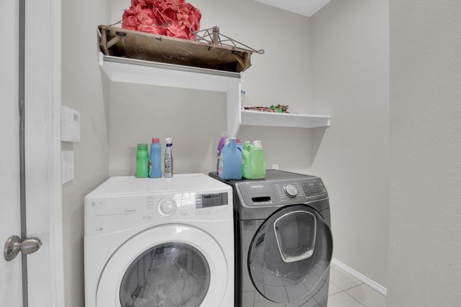 Washroom with light tile patterned floors, laundry area, baseboards, and washer and dryer | Image 24