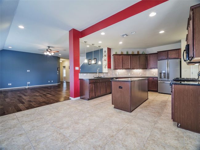 Kitchen featuring stainless steel refrigerator with ice dispenser, a center island, a ceiling fan, a sink, and open floor plan | Image 19