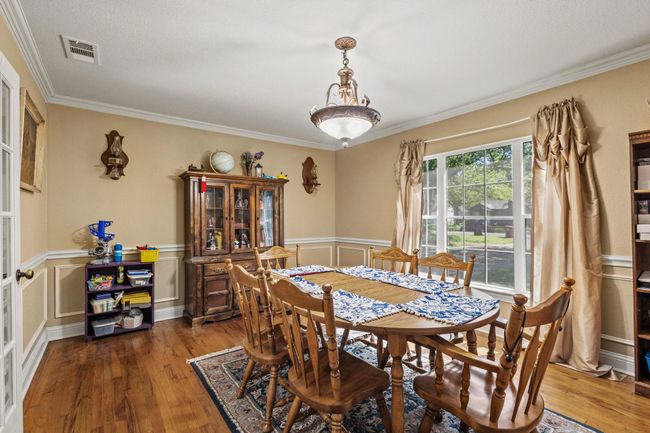 Dining space with wood finished floors, visible vents, ornamental molding, and wainscoting | Image 12