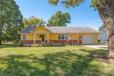 Ranch-style house with a front yard, a garage, and a porch | Image 1