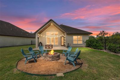 Step into serenity with this enchanting backyard retreat. Ideal for both tranquil relaxation and lively get-togethers, the centerpiece firepit casts a warm glow for unforgettable evenings under the stars. | Image 1