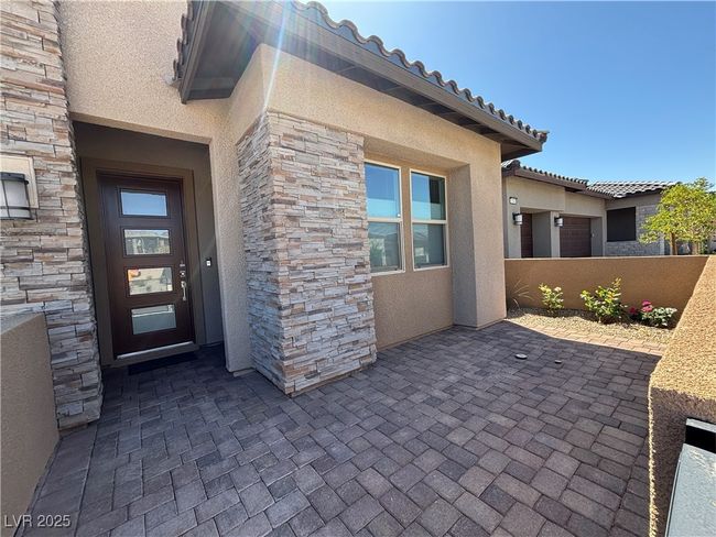 Entrance to property with a patio area, stone siding, stucco siding, and fence | Image 4