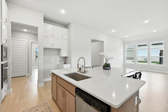 Kitchen with appliances with stainless steel finishes, light wood-style floors, a center island with sink, recessed lighting, and light countertops | Image 7