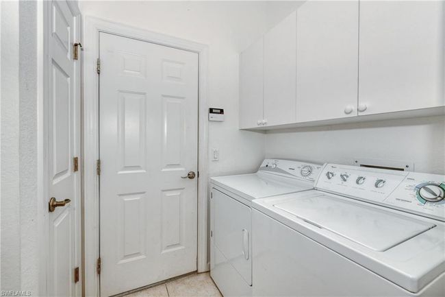Clothes washing area featuring cabinets, independent washer and dryer, and light tile patterned flooring | Image 9
