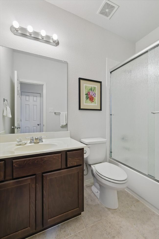 Full bath featuring shower / bath combination with glass door, toilet, vanity, and visible vents | Image 12