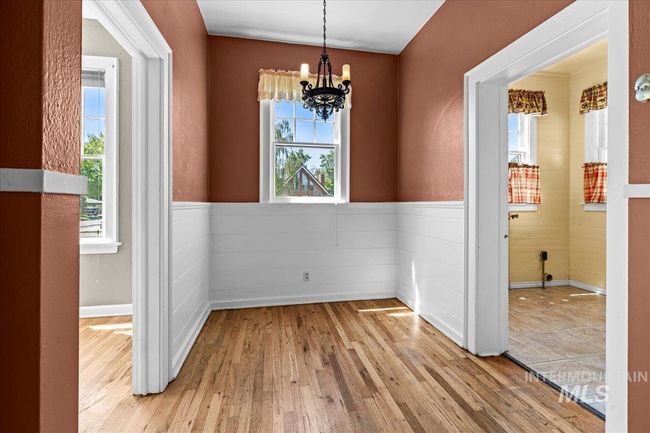 Unfurnished dining area featuring a chandelier, wood finished floors, and wainscoting | Image 12