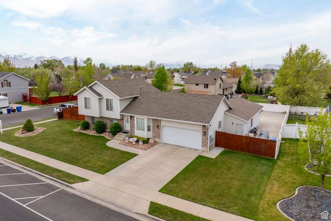 View of front facade featuring brick siding, a residential view, a front lawn, and a garage | Image 54