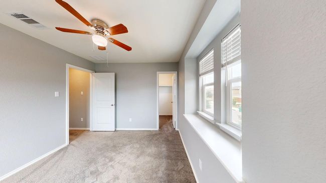 Unfurnished bedroom featuring visible vents, carpet floors, baseboards, a walk in closet, and ceiling fan | Image 34
