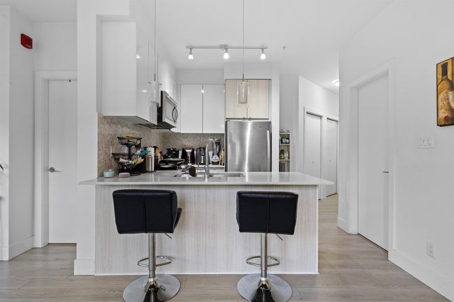 Kitchen with stainless steel appliances, modern cabinets, a peninsula, a kitchen bar, and light countertops | Image 14