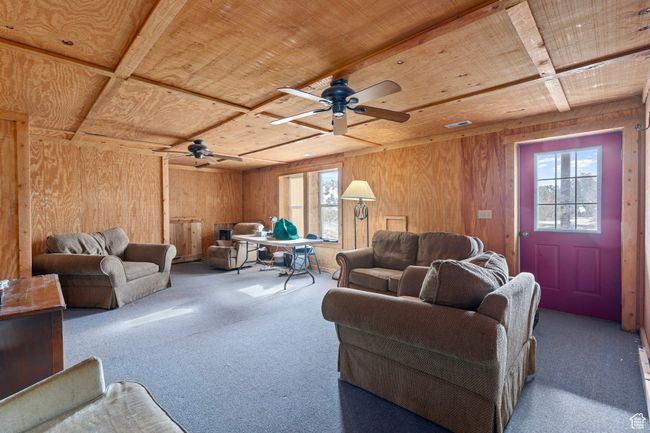 Living room with carpet floors, ceiling fan, wood walls, and wood ceiling | Image 8