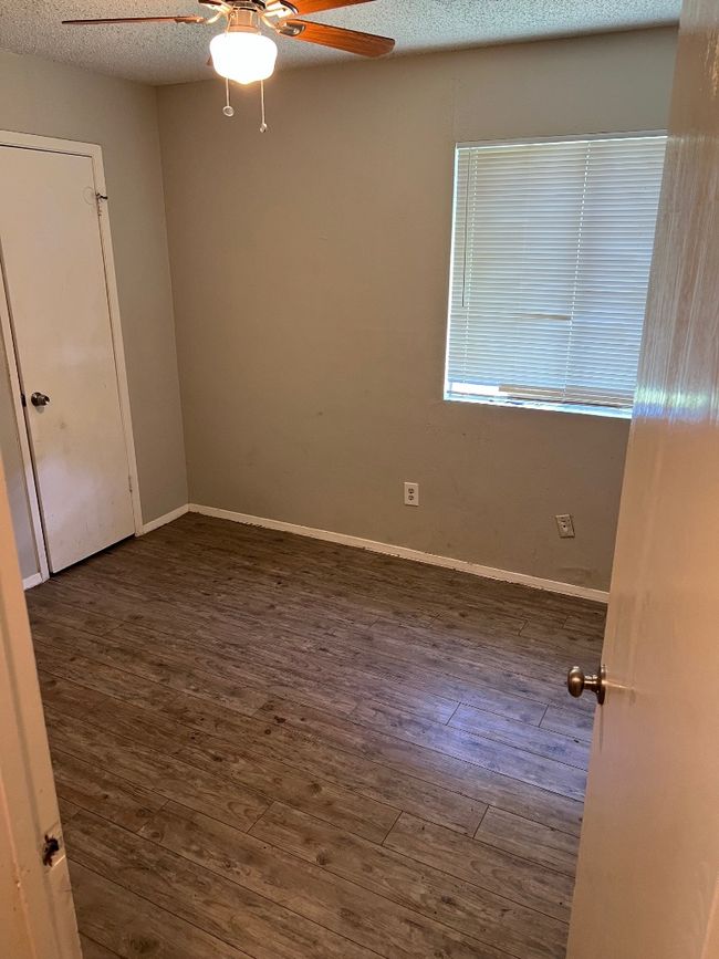 Empty room with a ceiling fan, wood finished floors, a textured ceiling, and baseboards | Image 11