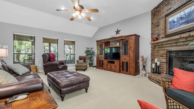 Living area with carpet floors, ceiling fan, vaulted ceiling, and a brick fireplace | Image 12