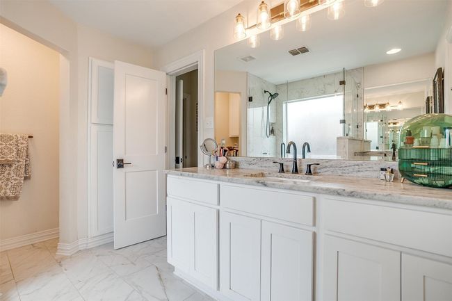 Full bath featuring a stall shower, vanity, and marble look tiles | Image 25