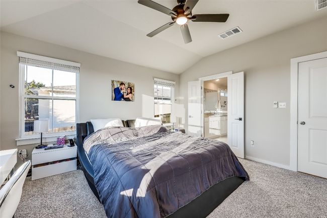 Bedroom featuring multiple windows, vaulted ceiling, light carpet, connected bathroom, and ceiling fan | Image 20